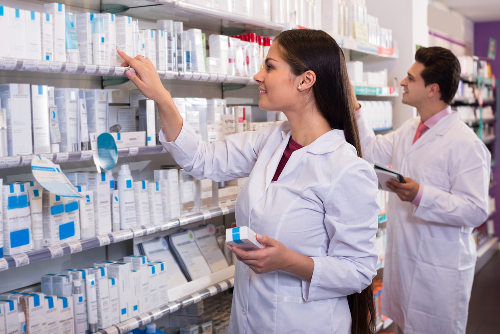 Smiling Pharmacist at Medication Shelf